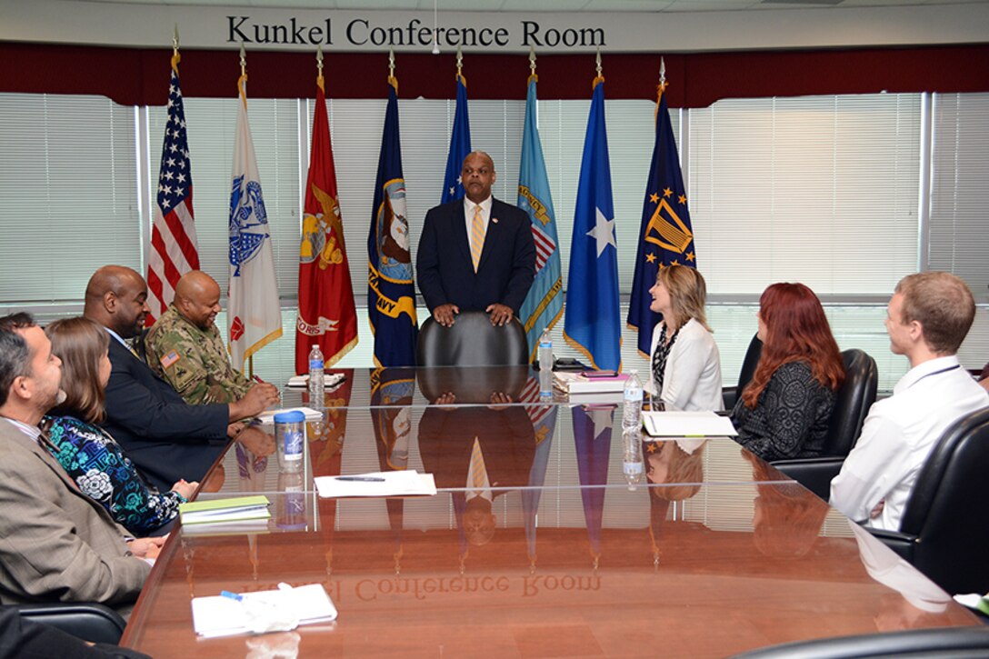 Retired Navy Rear Adm. Sinclair Harris stands at head of table while speaking to DLA Energy employees