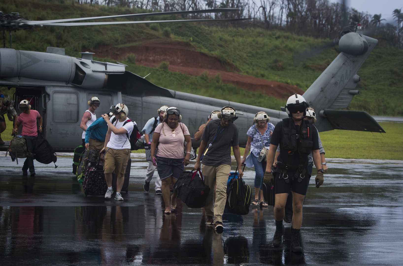 U.S. Sailors with Helicopter Sea Combat Squadron 22, supporting Joint Task Force - Leeward Islands , escort U.S. citizens to the evacuation control center  at Douglas-Charles Airport in Dominica, Sept. 24, 2017