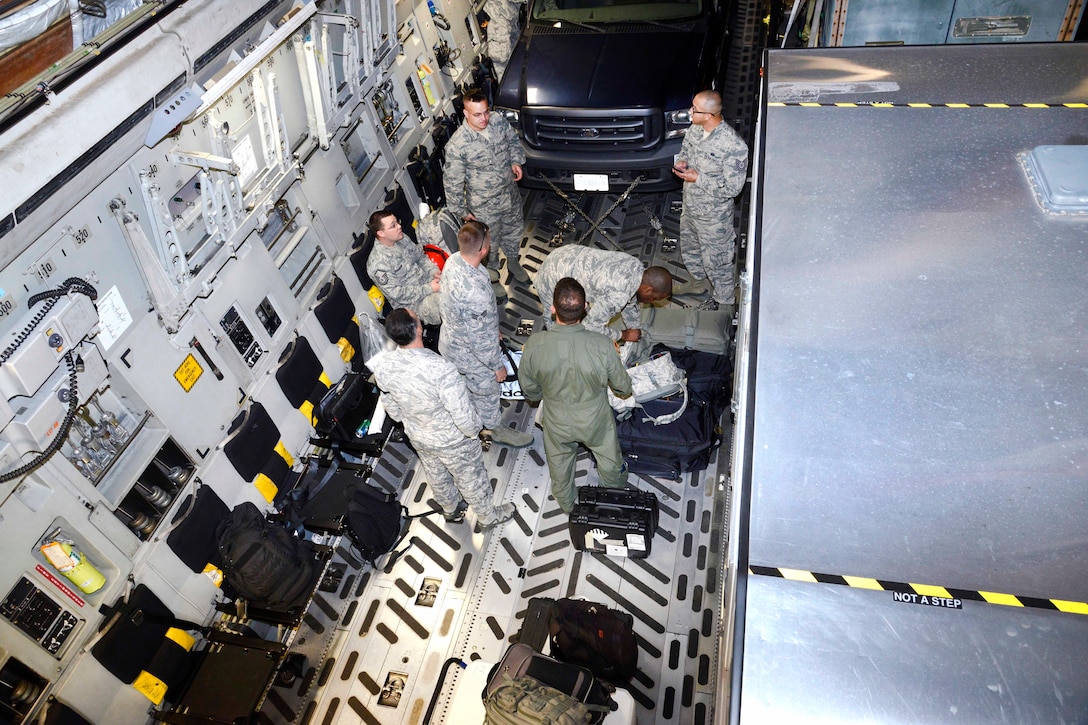 A group of airmen stand inside an aircraft.