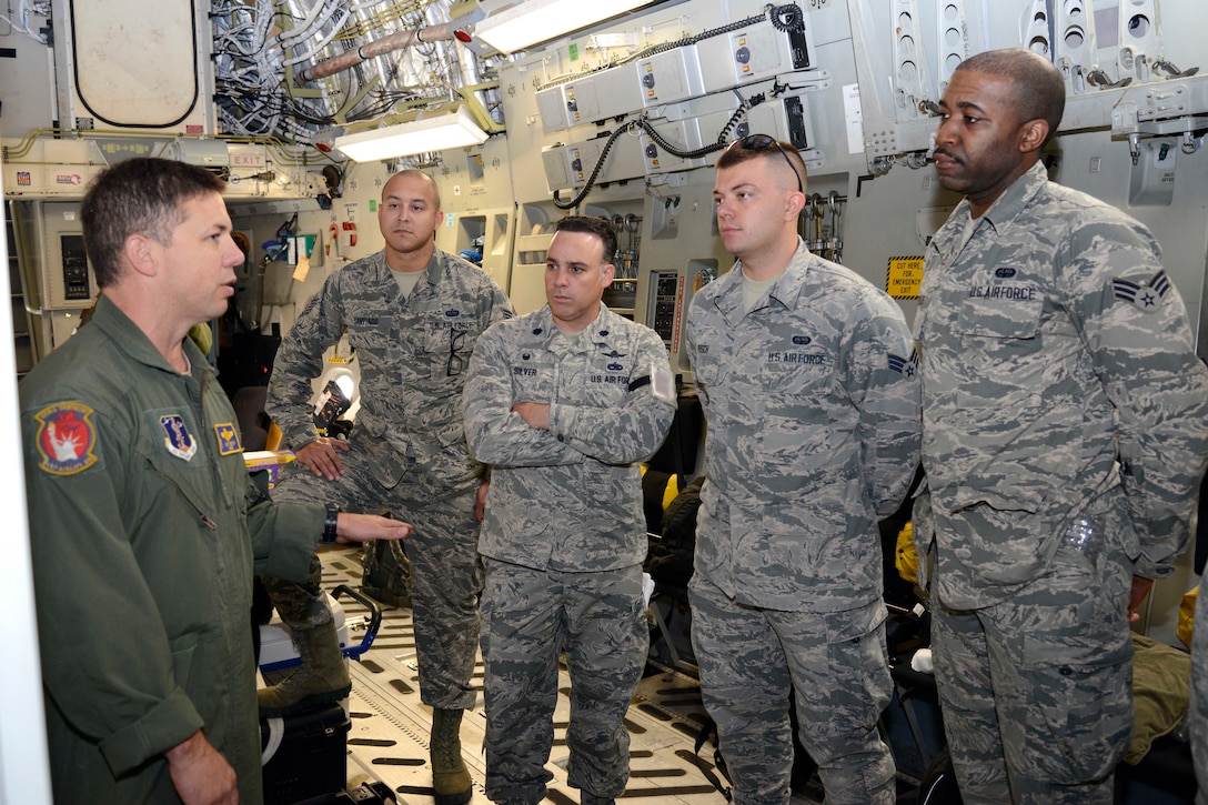 A group of airmen listen to another airman speak.