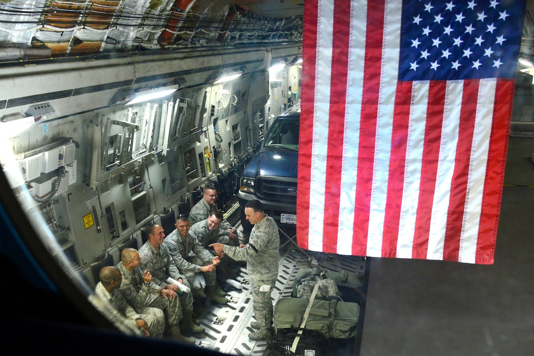 A group of airmen sit in an aircraft and talk.