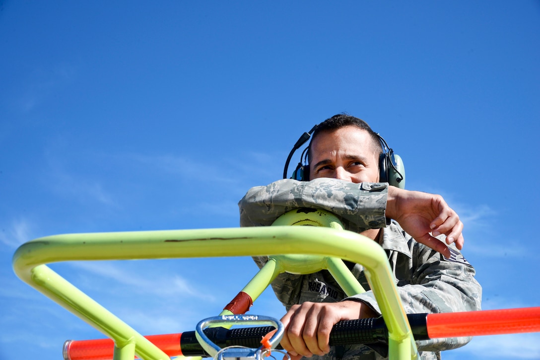 An airman leans on a railing looking at something out of the image.