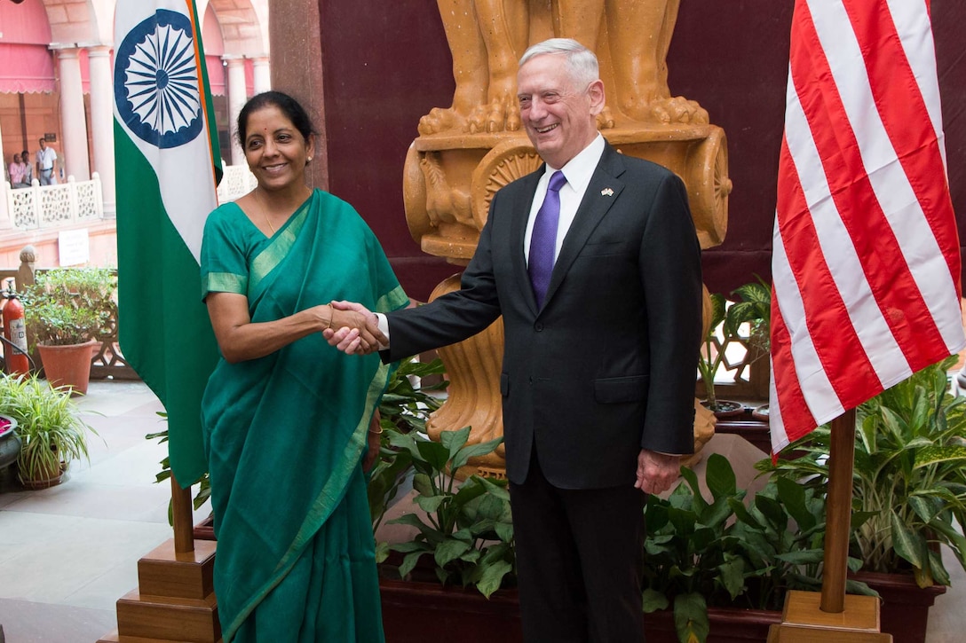 Defense Secretary shakes hands with Indian defense leader.