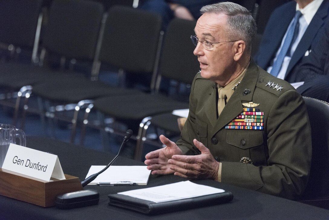 Marine Corps Gen. Joe Dunford sits at a table speaking to congressmen.