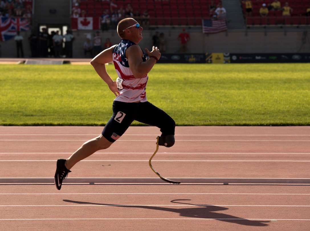 An athlete with one prosthetic leg sprints on a track.