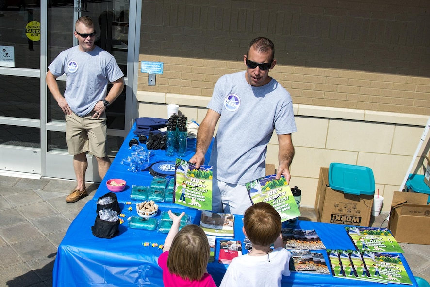 Tech. Sgt. Nick Olson, 23d Civil Engineer Squadron emergency management NCO in charge of training and logistics, hands coloring books to children at a local pet store, Sept. 23, 2017, in Valdosta, Ga. Members of the 23d CES hosted the event as part of National Preparedness Month to educate pet owners on disaster precautions. (U.S. Air Force photo by Airman 1st Class Erick Requadt)