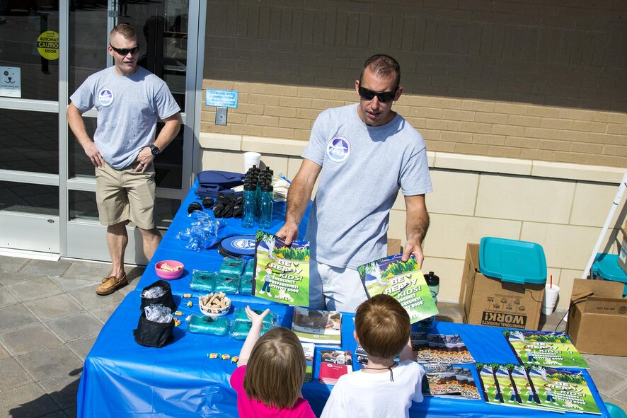 Tech. Sgt. Nick Olson, 23d Civil Engineer Squadron emergency management NCO in charge of training and logistics, hands coloring books to children at a local pet store, Sept. 23, 2017, in Valdosta, Ga. Members of the 23d CES hosted the event as part of National Preparedness Month to educate pet owners on disaster precautions. (U.S. Air Force photo by Airman 1st Class Erick Requadt)