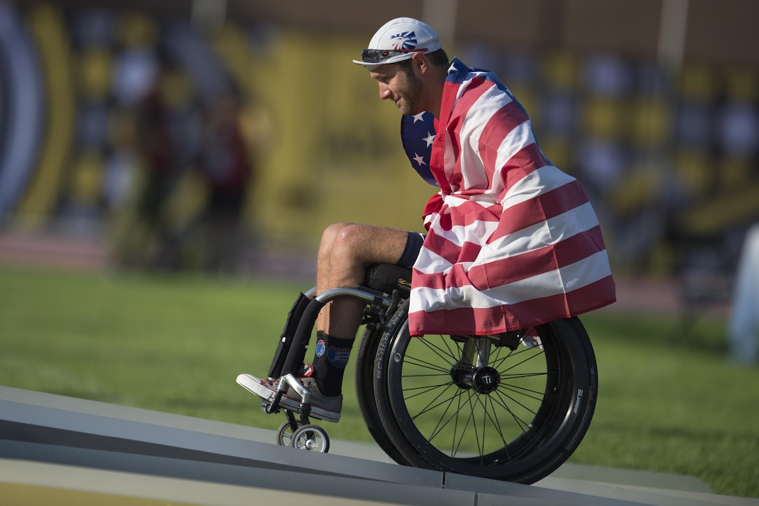 Medically retired Navy Petty Officer 3rd Class Nate DeWalt takes the medals stage to receive a gold medal in wheelchair racing.