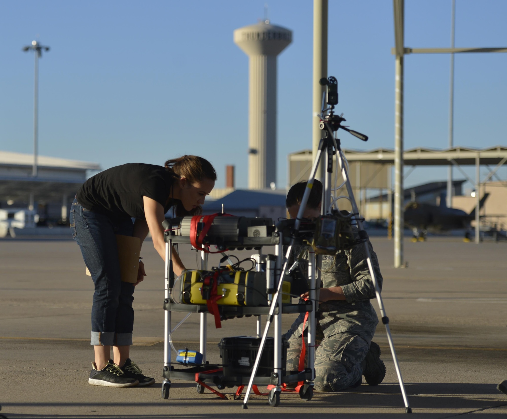 Danielle McKenzie-Smith, USAF School of Aerospace Medicine bioenvironmental engineer secures testing equipment on the flightline at Luke Air Force Base, Ariz., Sept. 20, 2017. McKenzie-Smith and the team strategically placed equipment to test chemicals, particle sizes and the distribution of particles in the air related  to the F-35A Lightning II program.  (U.S. Air Force photo/Airman 1st Class Caleb Worpel)