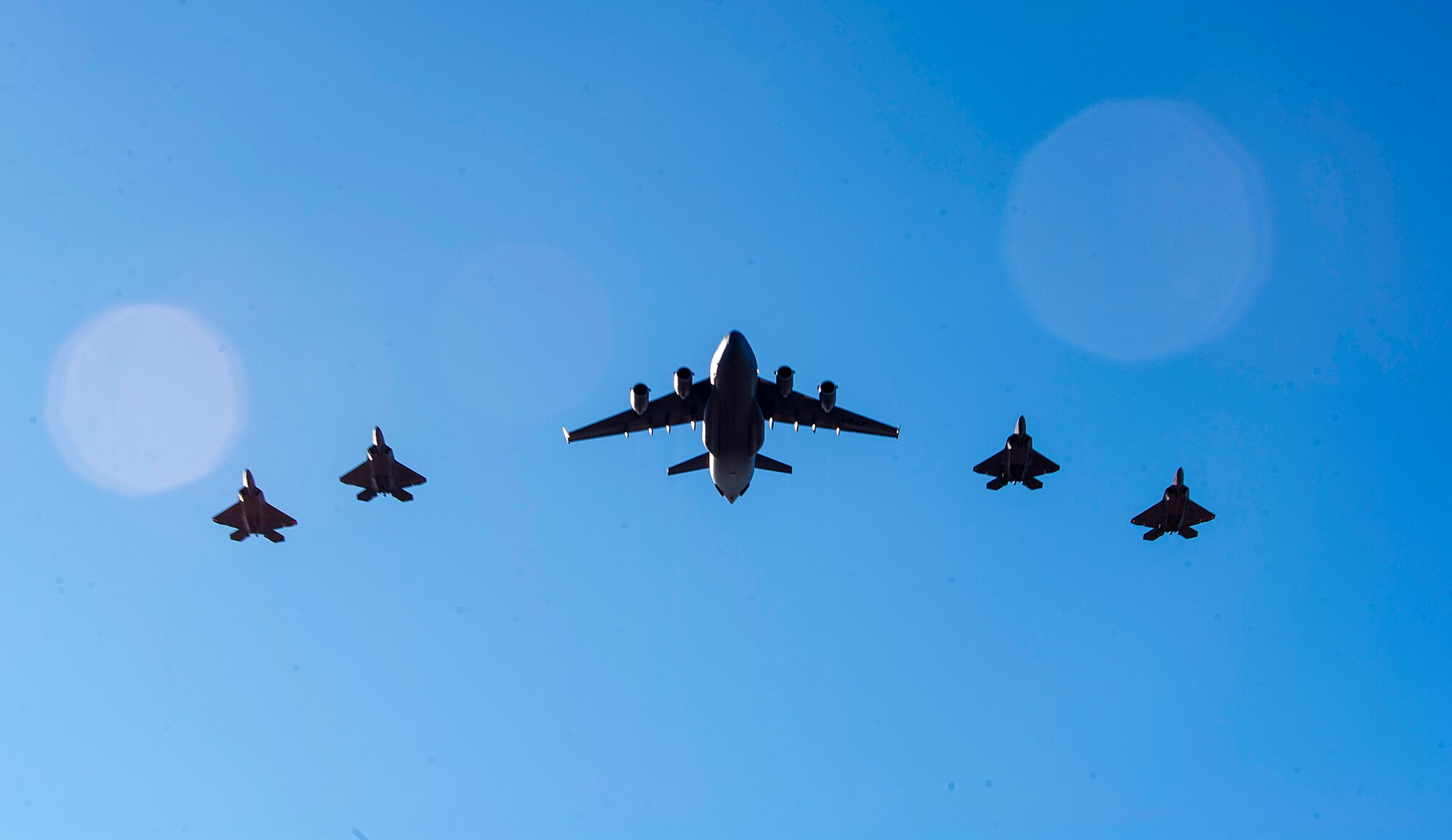 A C-17 Globemaster III and four F-22 Raptors fly in formation over Joint Base Pearl Harbor-Hickam, HI, Sept. 26, 2017.
