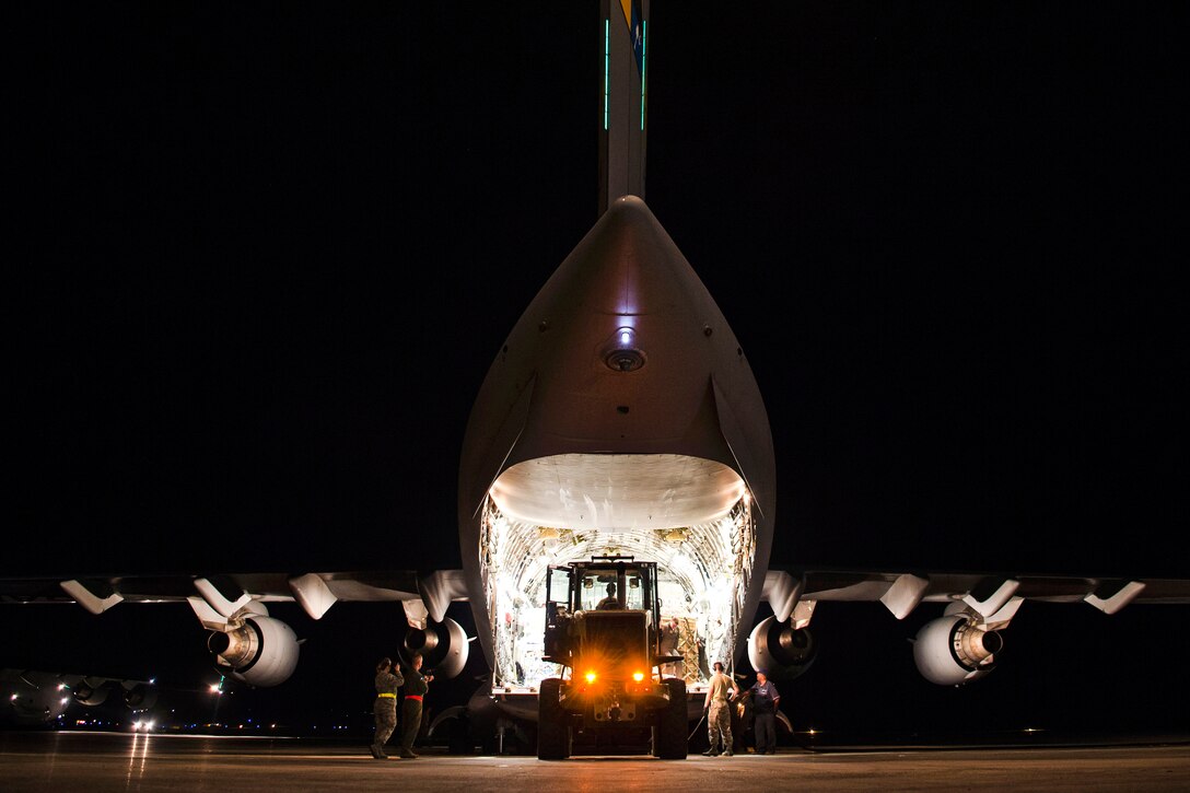 Airmen offload humanitarian aid and equipment from a C-17 Globemaster III aircraft.