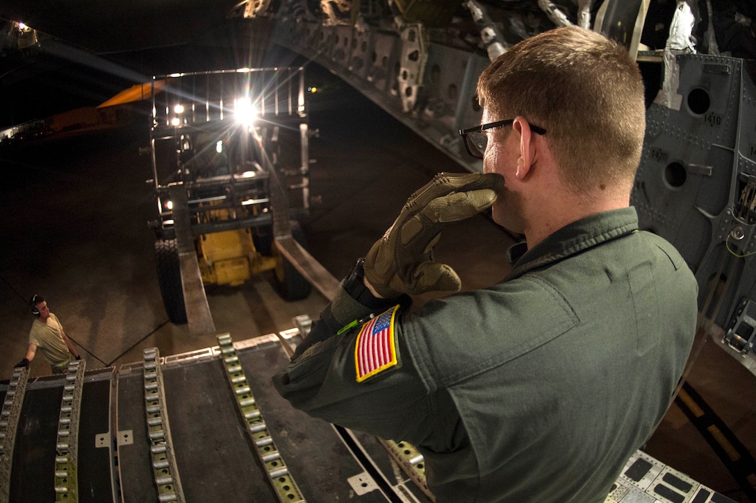 Air Force Senior Airman Mark Darnell directs a forklift toward a C-17 Globemaster III aircraft to receive water and food.