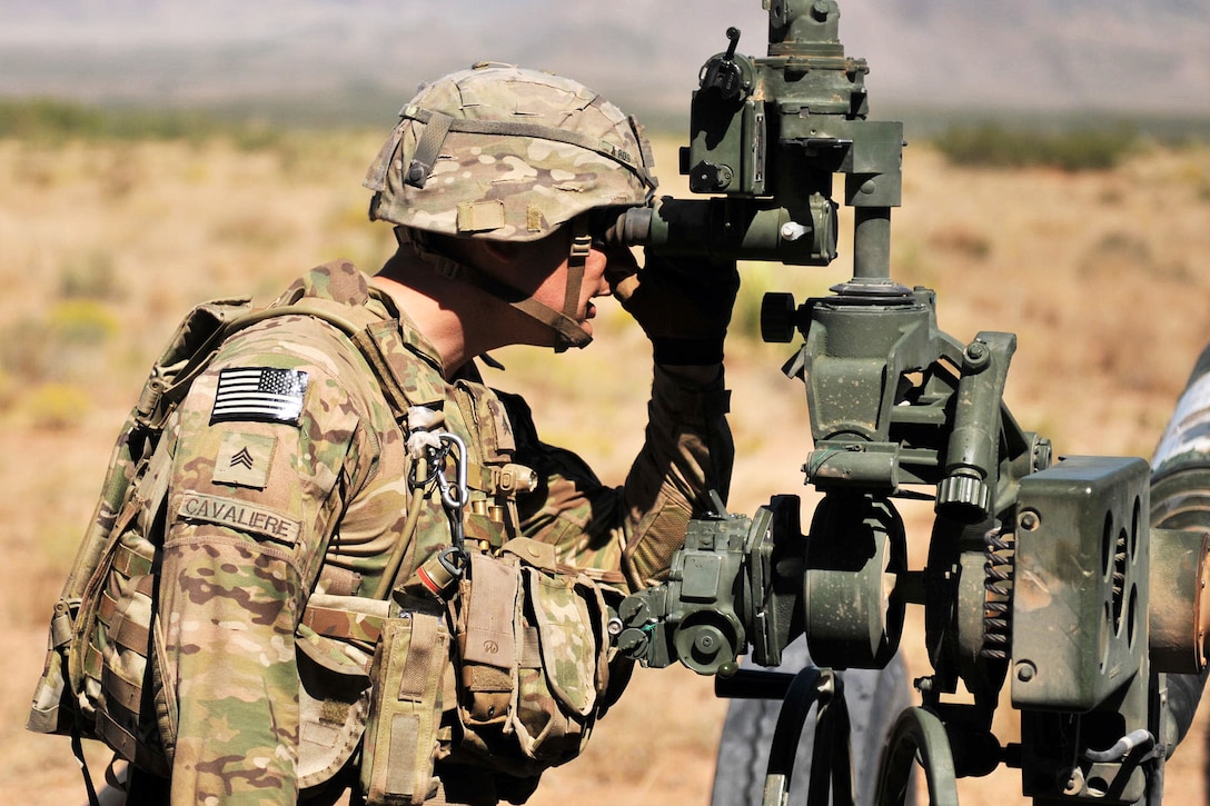 Army Sgt. Douglas Cavaliere looks into the viewing glass on a M777 howitzer.