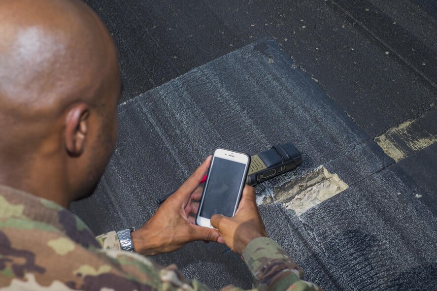 Staff Sgt. Dionta Bolding, 380th Expeditionary Operations Support Squadron deputy airfield manager, takes a photo of a spall, a small pothole or imperfection on a flightline, September 21, 2017, at Al Dhafra Air Base, United Arab Emirates.