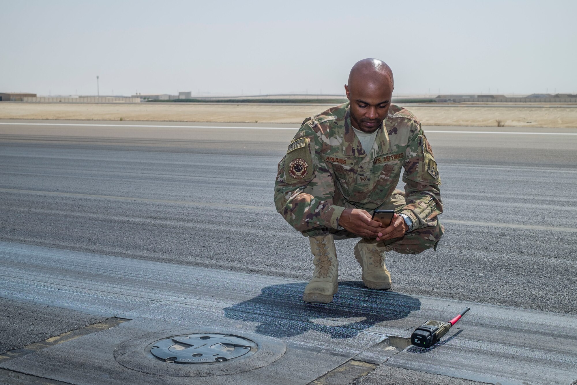 Staff Sgt. Dionta Bolding, 380th Expeditionary Operations Support Squadron deputy airfield manager, takes a photo of a spall, a small pothole or imperfection on a flightline, September 21, 2017, at Al Dhafra Air Base, United Arab Emirates.