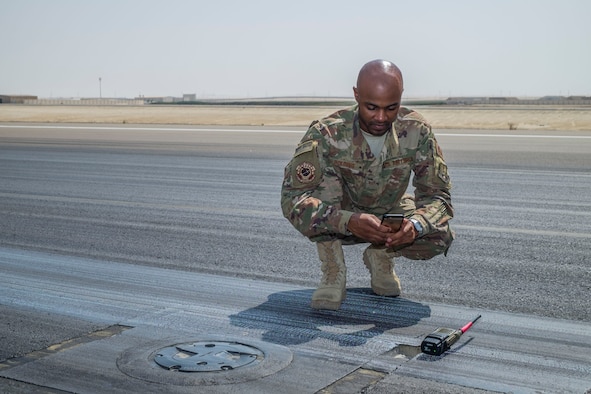 Staff Sgt. Dionta Bolding, 380th Expeditionary Operations Support Squadron deputy airfield manager, takes a photo of a spall, a small pothole or imperfection on a flightline, September 21, 2017, at Al Dhafra Air Base, United Arab Emirates.