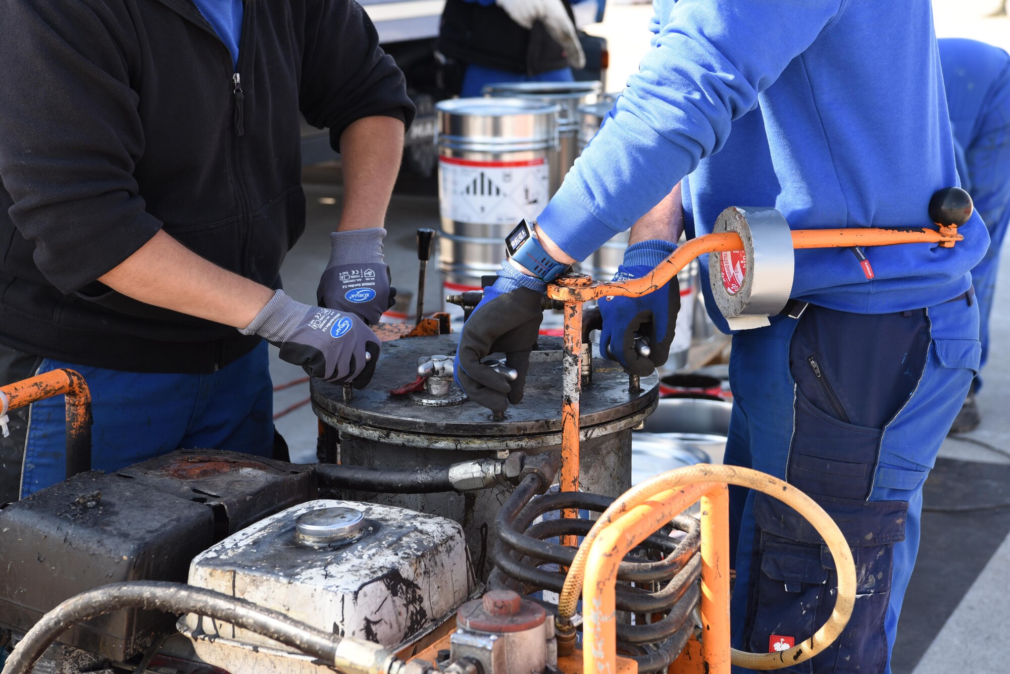 German contract workers prepare tar that will be placed on the flightline on Ramstein Air Base, Germany Sept. 21, 2017. In order for the tar to be more effective in the drains, it was heated on site. (U.S. Air Force photo by Airman 1st Class Milton Jr. Hamilton)