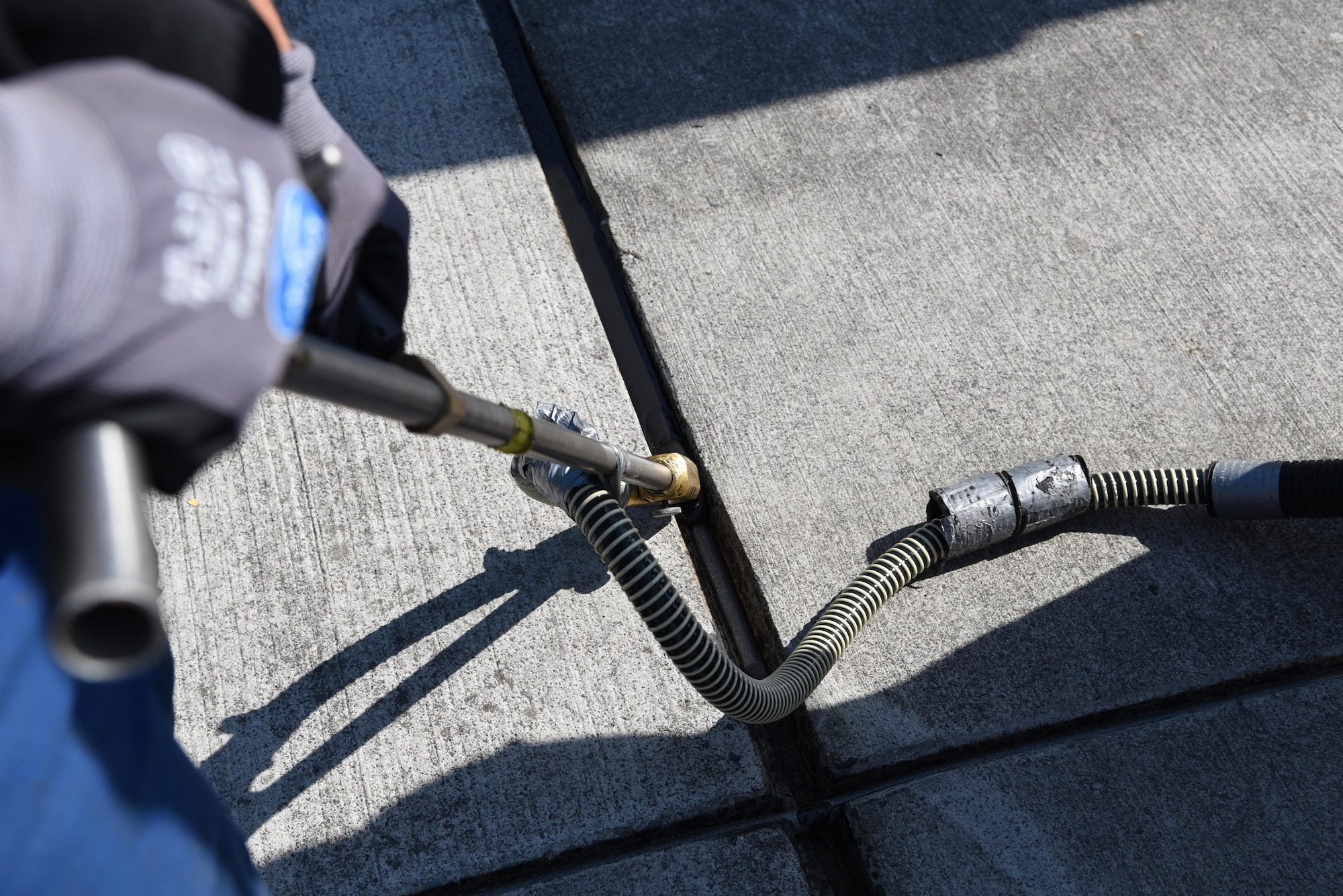 A German contractor adjusts his tools to inject tar in the drains of Ramp 5 on Ramstein Air Base, Germany Sept 21, 2017. This special tool is able to fit between the smallest cracks to apply the heated tar on the flightline. (U.S. Air Force photo by Airman 1st Class Milton Jr. Hamilton)
