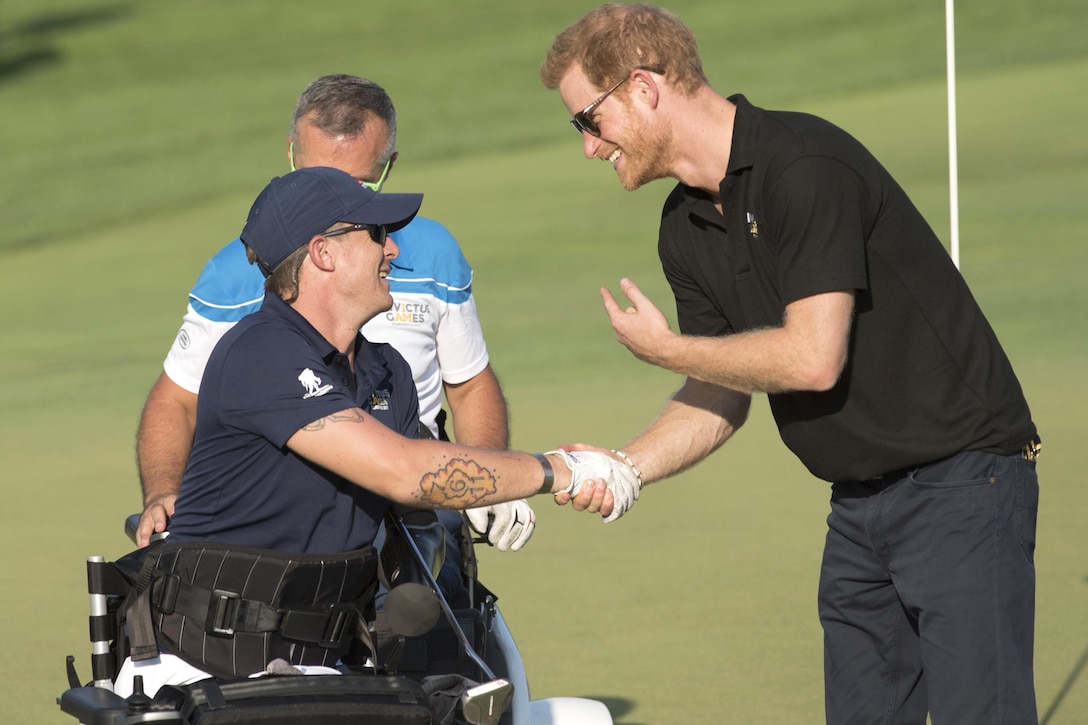 Marine Corps veteran Sgt. Michael Nicholson is congratulated by Britain's Prince Harry after competing in golf.