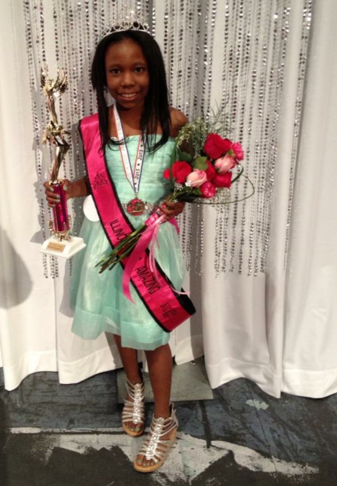 Iyana holds a trophy and wears a sash for her win in the Miss Amazing Illinois, which seeks to increase the self-confidence of young women with disabilities.  “She didn’t want to be classified as having sickle cell disease; she wanted to be classified as Iyana,” said her mother, Tech. Sgt. Shonda Blanks, 375th Operations Support Squadron commander’s support staff NCOIC. “That’s who she was as a person.  She was very sweet - had the biggest, prettiest smile, and was very nice to people.”  (Photo courtesy)