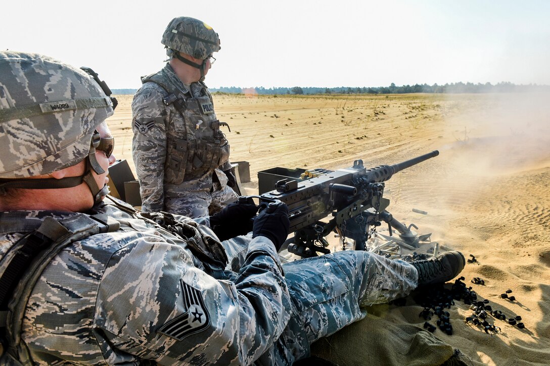 Staff Sgt. Andrew Donovan Wilson, foreground, fires a M2 machine gun at targets while Senior Airman Kyle Smithwick looks on during heavy weapons training