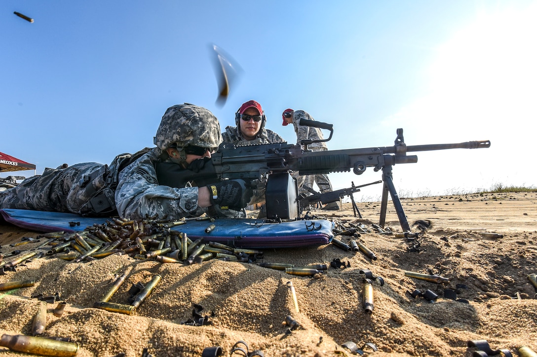 Staff Sgt. Julio Medina, foreground, fires an M249 machine gun at his target while Tech. Sgt. Ismeal Fierro looks on during heavy weapons training.