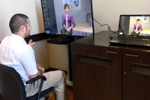 A person sits in a chair looking at computer screens.