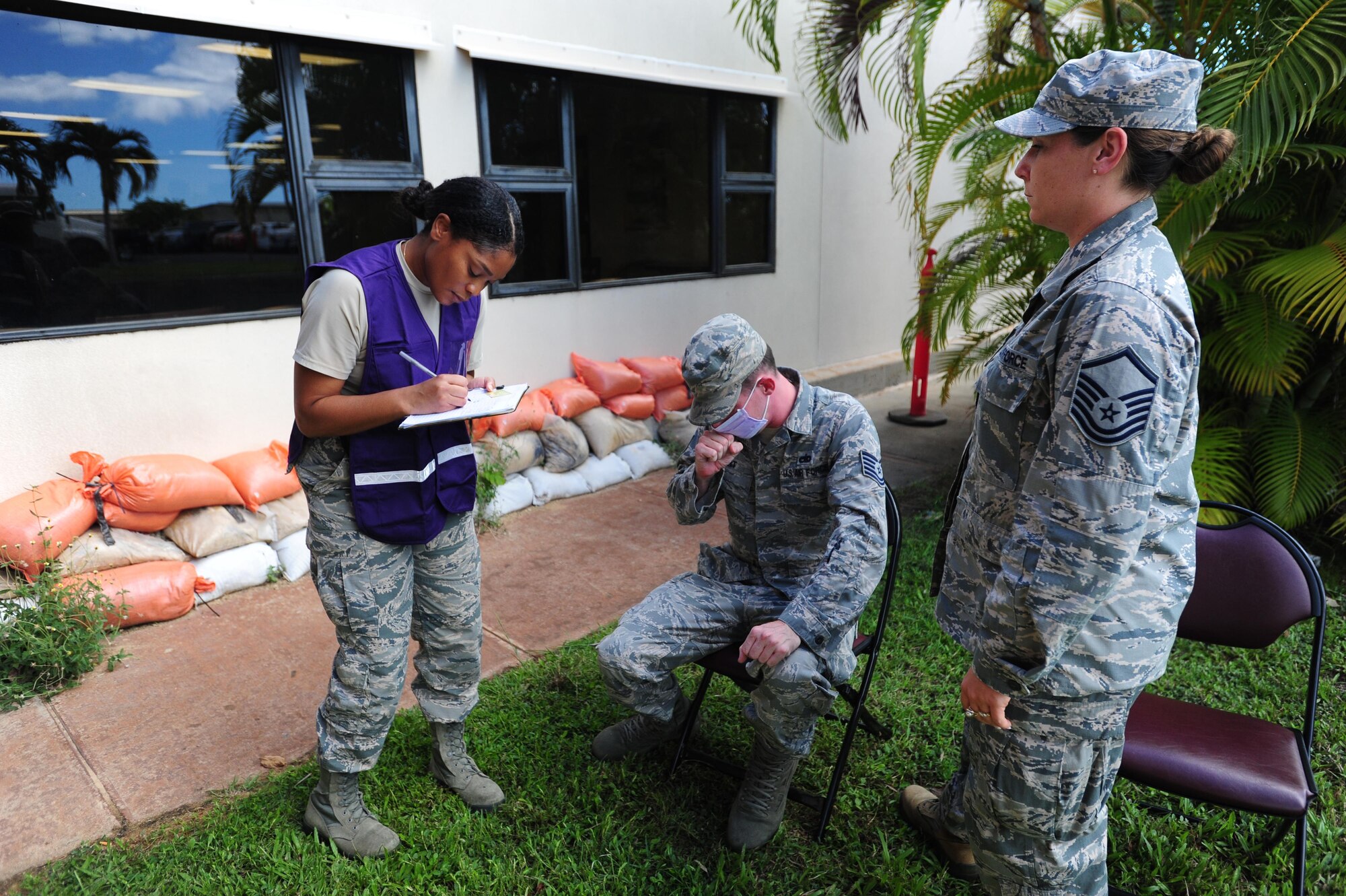 Medical technician writes down symptoms as a patient coughs and another looks on.