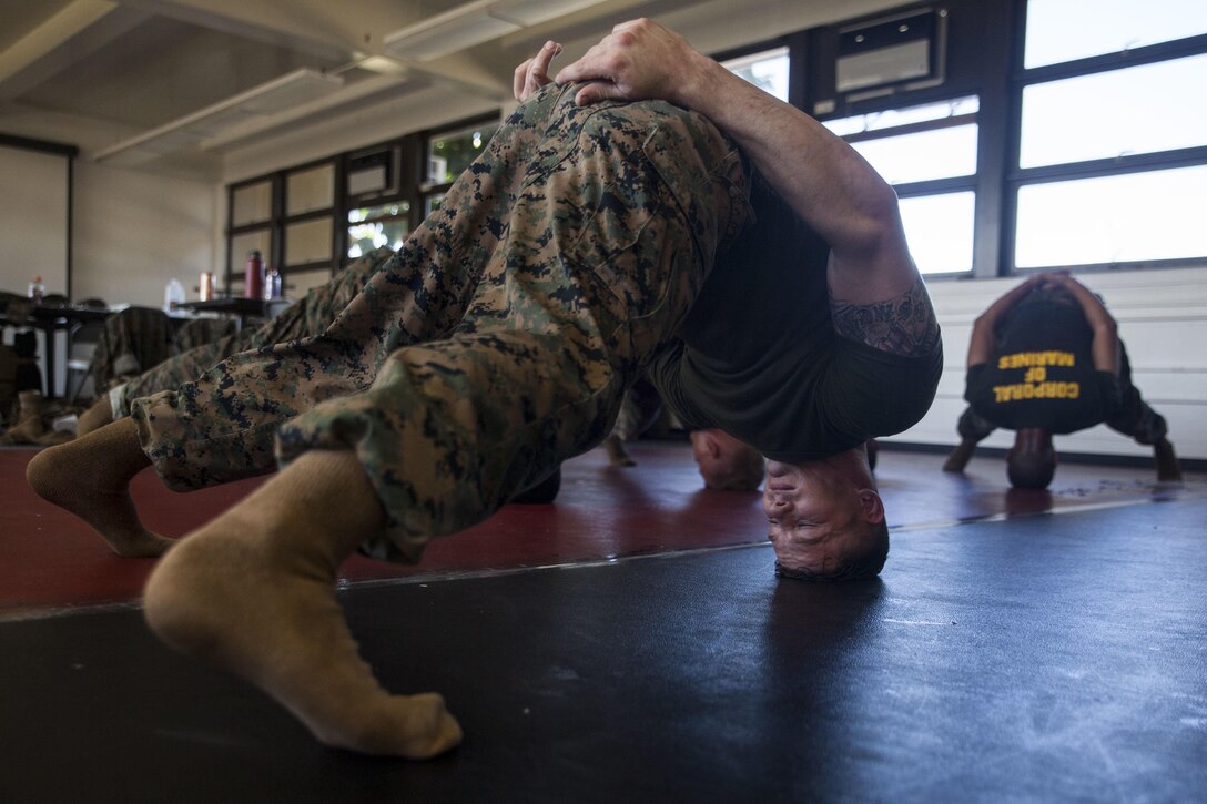 Sgt. Charles Johnson, a fire directions center chief with Weapons Company, 2nd Battalion, 3rd Marine Regiment, conducts a tripod stretch during a Martial Arts Instructor Course (MAIC), Marine Corps Base Hawaii (MCBH), Sept. 21, 2017. MAIC is a 3-week course designed to enable Marines to teach their own future Marine Corps Martial Arts Program (MCMAP) classes, and reward them with the next tier MCMAP belt upon successful completion of a class. (U.S. Marine Corps photo by Cpl. Jesus Sepulveda Torres)