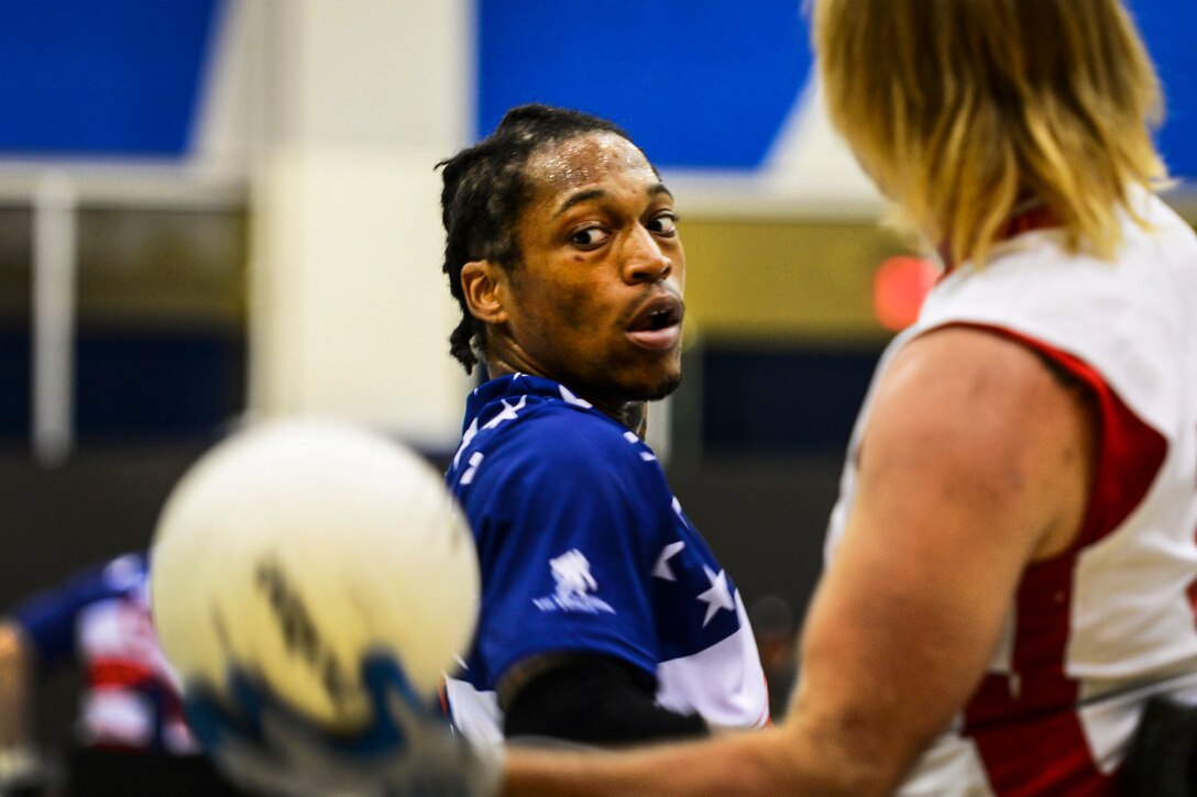 An athlete watches a competitor holding a ball.