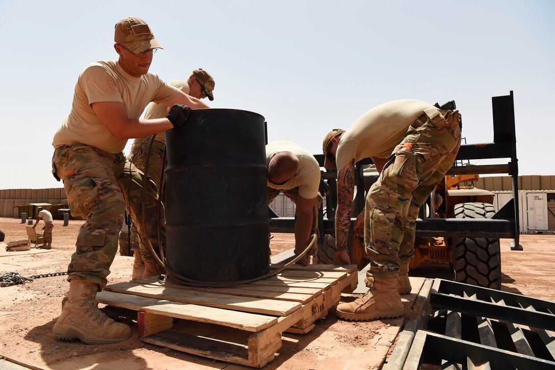 Airmen move barrels of gas.