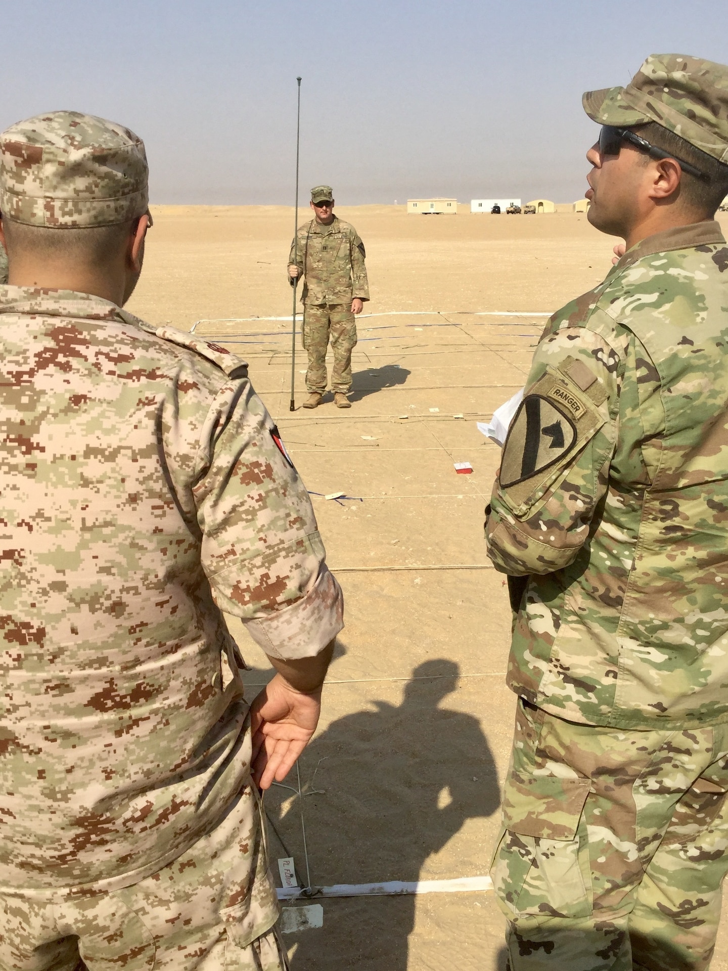 One solider briefs the mission while two others look on.