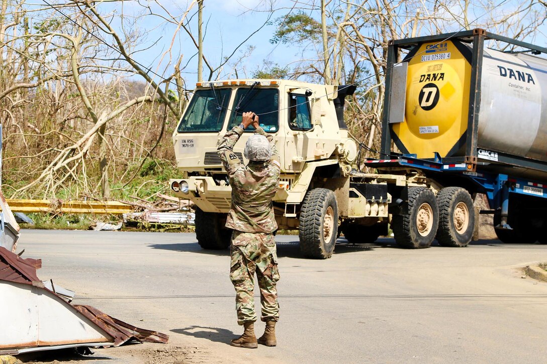 A Guardsman clears a power line for a truck transporting a large amount of water to be distributed to residents in the San Jose community in Toa Baja.