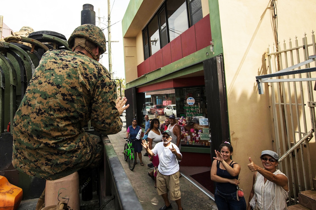 A Marine waves to residents.