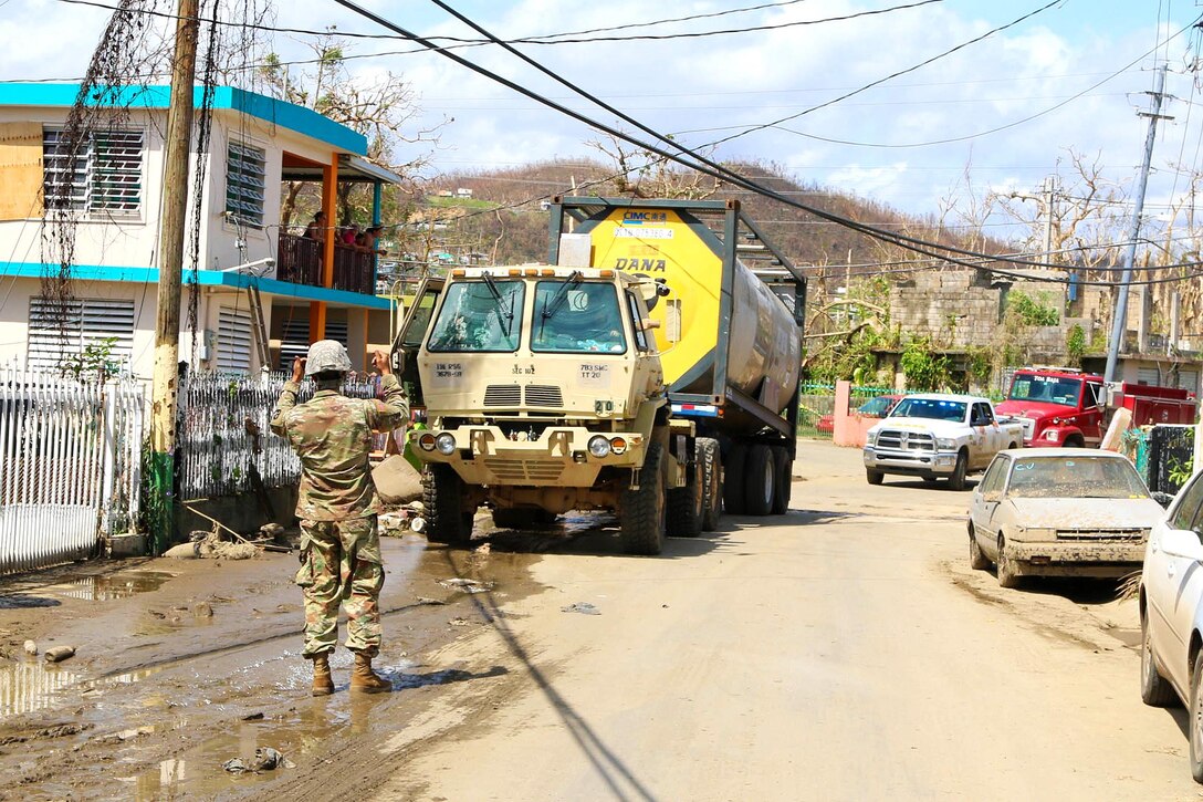 A Guardsman ground guides while directing a truck transporting a large amount of water to be distributed to residents in the San Jose community in Toa Baja.