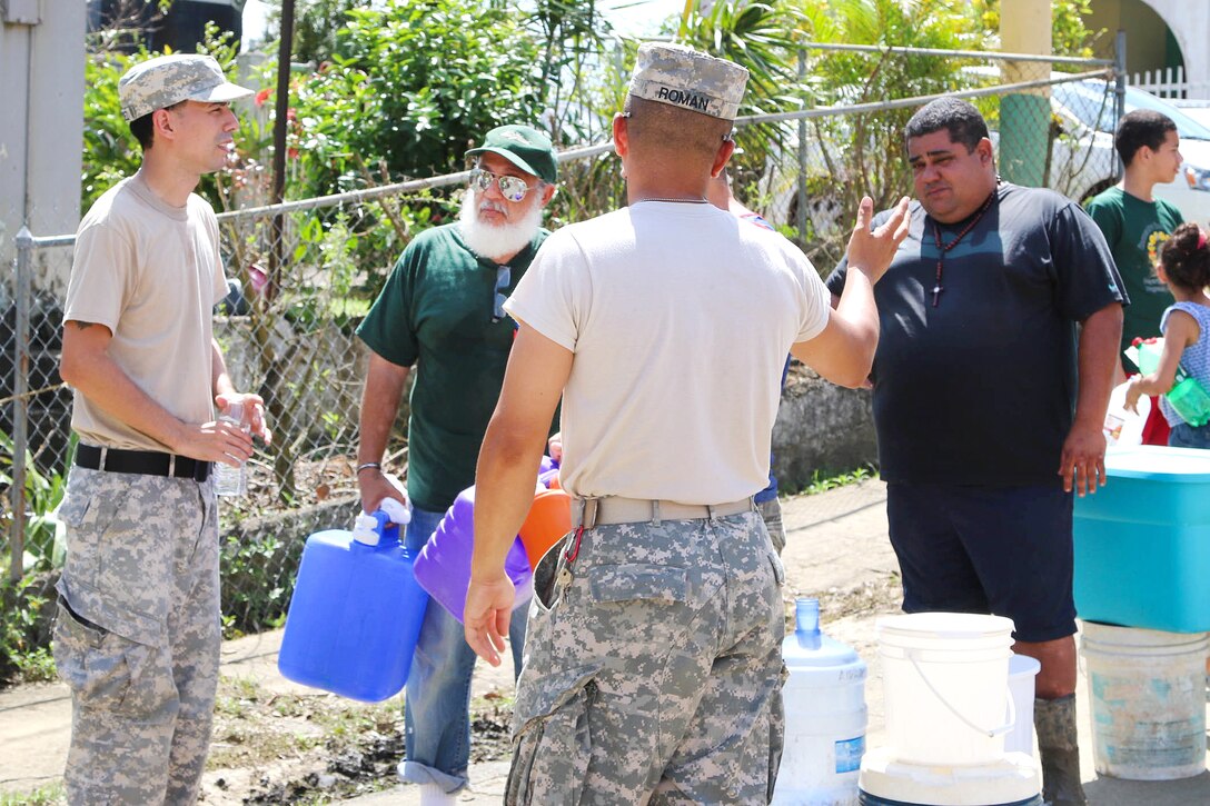 Guardsmen distribute water to residents in the San Jose community in Toa Baja.