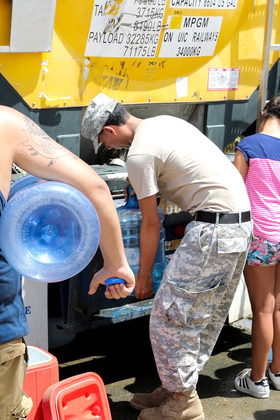 Guardsmen distribute water to residents in the San Jose community in Toa Baja.