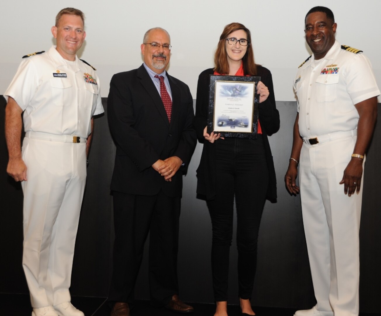 IMAGE: DAHLGREN, Va. - Kimberly Howell receives her certificate of achievement from Naval Surface Warfare Center Dahlgren Division (NSWCDD) Technical Director John Fiore, NSWCDD Commanding Officer Capt. Godfrey 'Gus' Weekes, right, and Combat Direction Systems Activity Dam Neck Commanding Officer Cmdr. Andrew Hoffman at the 2017 NSWCDD academic awards ceremony. Howell was recognized for completing her bachelor's in mathematics from Virginia Tech, and commended for her commitment to personal and professional development.