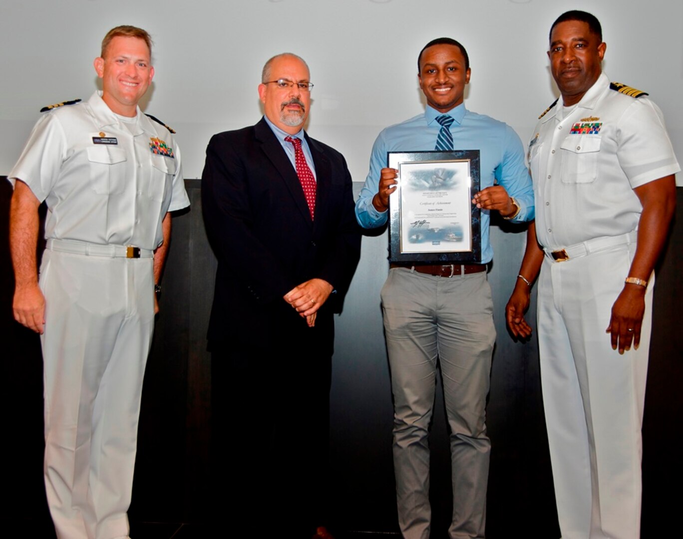 IMAGE: DAHLGREN, Va. - James Finnie receives his certificate of achievement from Naval Surface Warfare Center Dahlgren Division (NSWCDD) Technical Director John Fiore, NSWCDD Commanding Officer Capt. Godfrey 'Gus' Weekes, right, and Combat Direction Systems Activity Dam Neck Commanding Officer Cmdr. Andrew Hoffman at the 2017 NSWCDD academic awards ceremony. Finnie was recognized for completing his master's in cybersecurity engineering from Morgan State University, and commended for his commitment to personal and professional development.