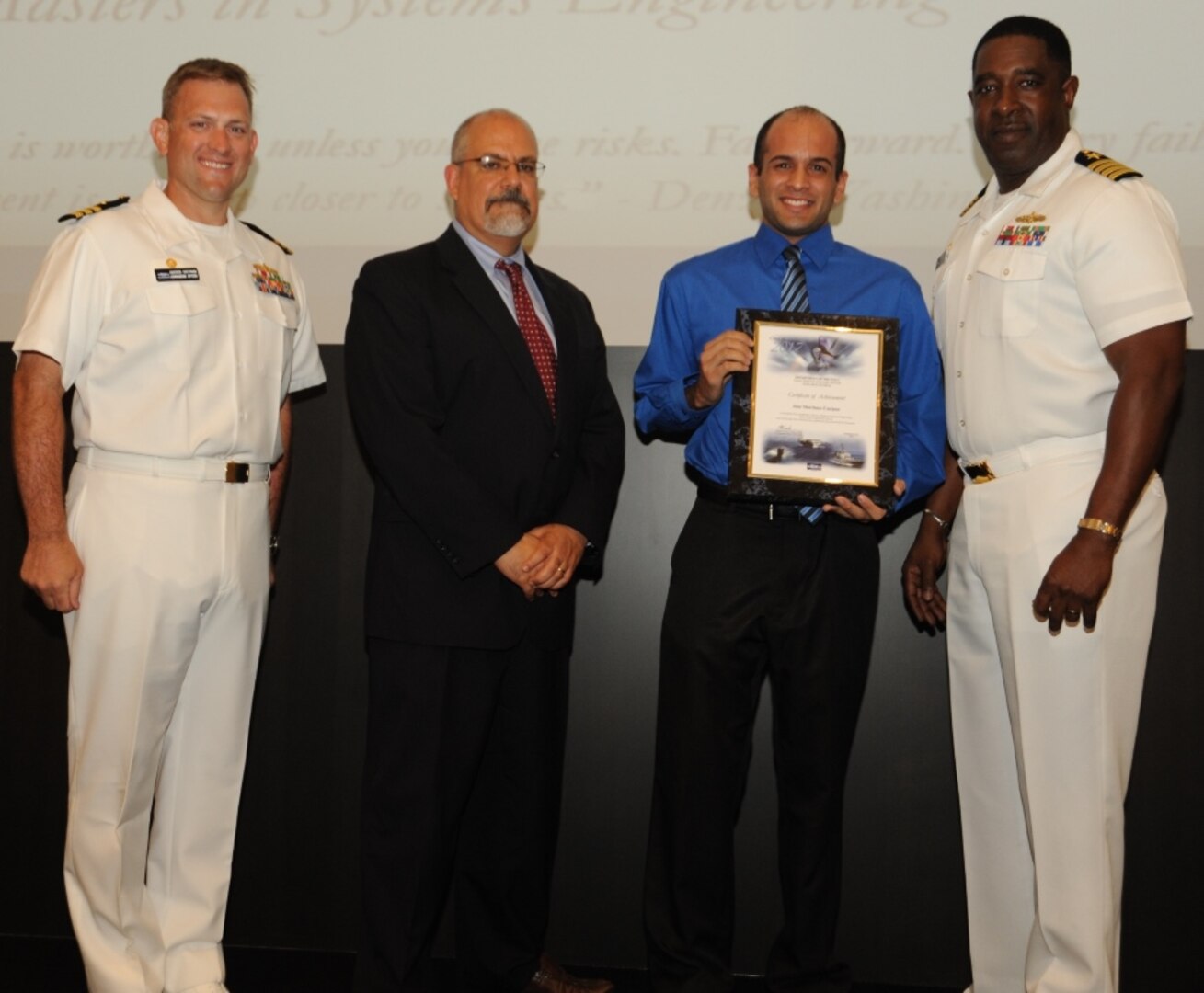 IMAGE: DAHLGREN, Va. - Jose Martinez-Casiano receives his certificate of achievement from Naval Surface Warfare Center Dahlgren Division (NSWCDD) Technical Director John Fiore, NSWCDD Commanding Officer Capt. Godfrey 'Gus' Weekes, right, and Combat Direction Systems Activity Dam Neck Commanding Officer Cmdr. Andrew Hoffman at the 2017 NSWCDD academic awards ceremony. Martinez-Casiano was recognized for completing his master's in systems engineering from the Naval Postgraduate School, and commended for his commitment to personal and professional development.