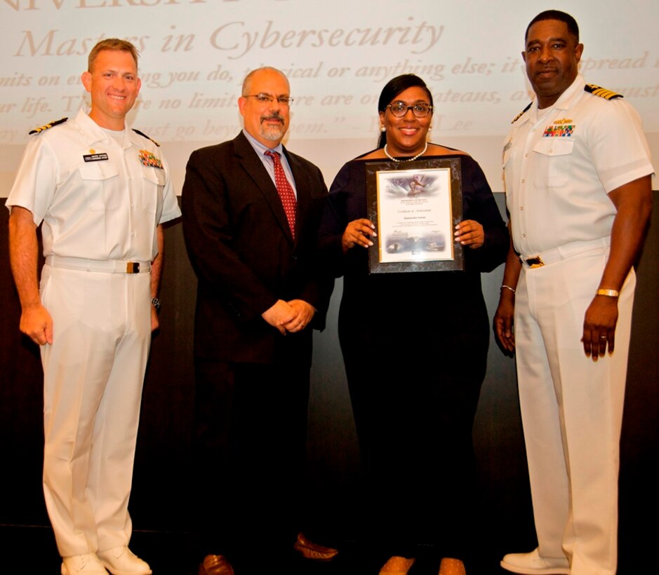 IMAGE: DAHLGREN, Va. - Quinnesha Staton receives her certificate of achievement from Naval Surface Warfare Center Dahlgren Division (NSWCDD) Technical Director John Fiore, NSWCDD Commanding Officer Capt. Godfrey 'Gus' Weekes, right, and Combat Direction Systems Activity Dam Neck Commanding Officer Cmdr. Andrew Hoffman at the 2017 NSWCDD academic awards ceremony. Staton was recognized for completing her master's in cybersecurity from the University of Maryland University College, and commended for her commitment to personal and professional development.