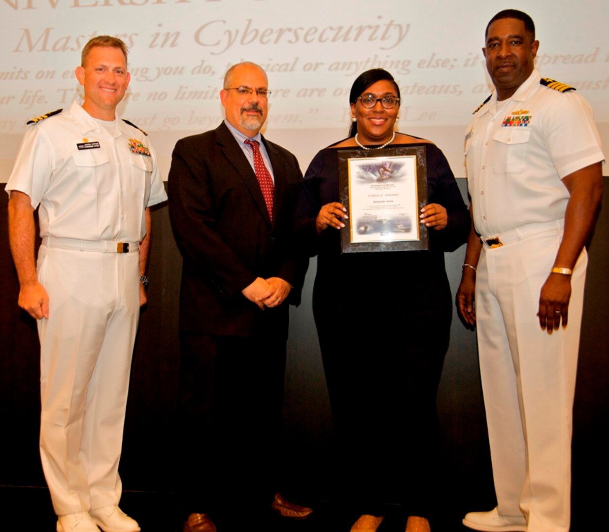 IMAGE: DAHLGREN, Va. - Quinnesha Staton receives her certificate of achievement from Naval Surface Warfare Center Dahlgren Division (NSWCDD) Technical Director John Fiore, NSWCDD Commanding Officer Capt. Godfrey 'Gus' Weekes, right, and Combat Direction Systems Activity Dam Neck Commanding Officer Cmdr. Andrew Hoffman at the 2017 NSWCDD academic awards ceremony. Staton was recognized for completing her master's in cybersecurity from the University of Maryland University College, and commended for her commitment to personal and professional development.