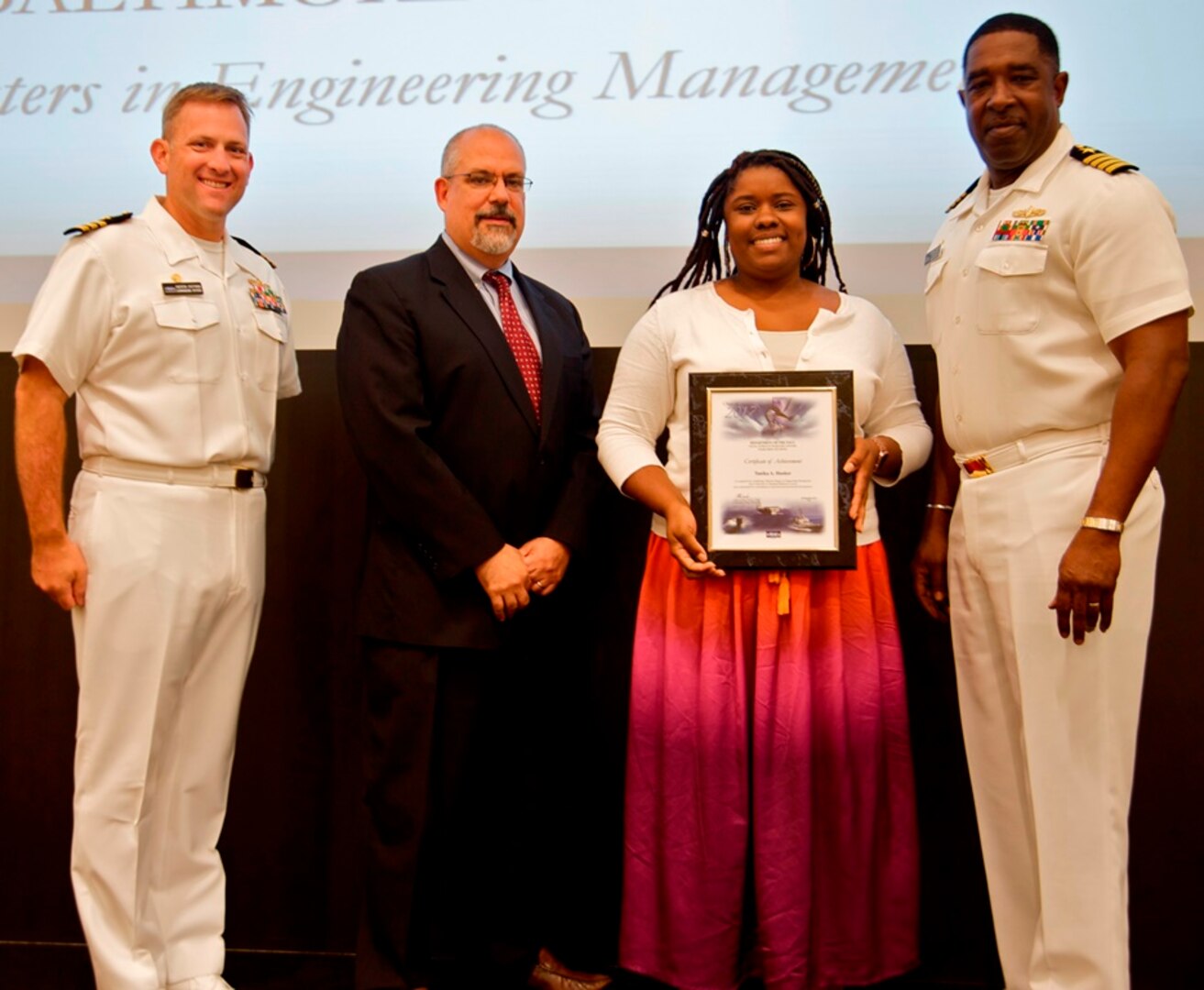 IMAGE: DAHLGREN, Va. - Tanika Hooker receives her certificate of achievement from Naval Surface Warfare Center Dahlgren Division (NSWCDD) Technical Director John Fiore, NSWCDD Commanding Officer Capt. Godfrey 'Gus' Weekes, right, and Combat Direction Systems Activity Dam Neck Commanding Officer Cmdr. Andrew Hoffman at the 2017 NSWCDD academic awards ceremony. Hooker was recognized for completing her master's in engineering management from the University of Maryland University College, and commended for her commitment to personal and professional development.