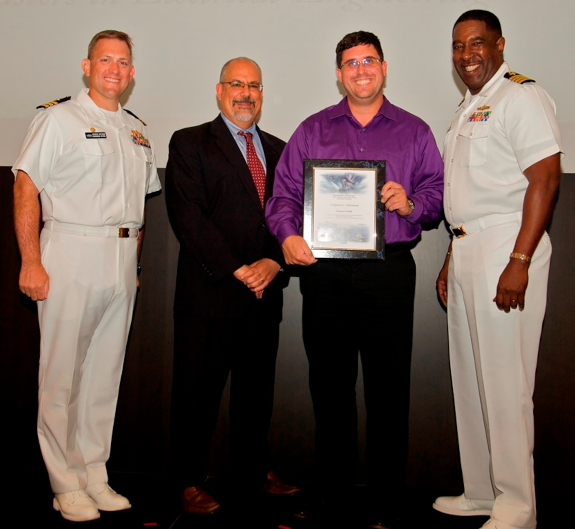 IMAGE: DAHLGREN, Va. - Cameron Sorlie receives his certificate of achievement from Naval Surface Warfare Center Dahlgren Division (NSWCDD) Technical Director John Fiore, NSWCDD Commanding Officer Capt. Godfrey 'Gus' Weekes, right, and Combat Direction Systems Activity Dam Neck Commanding Officer Cmdr. Andrew Hoffman at the 2017 NSWCDD academic awards ceremony. Sorlie was recognized for completing his master's in electrical engineering from John Hopkins University, and commended for his commitment to personal and professional development.