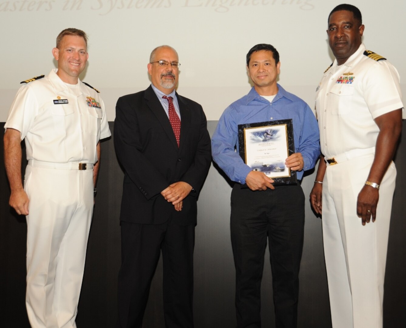 IMAGE: DAHLGREN, Va. - Tu Ngo receives his certificate of achievement from Naval Surface Warfare Center Dahlgren Division (NSWCDD) Technical Director John Fiore, NSWCDD Commanding Officer Capt. Godfrey 'Gus' Weekes, right, and Combat Direction Systems Activity Dam Neck Commanding Officer Cmdr. Andrew Hoffman at the 2017 NSWCDD academic awards ceremony. Ngo was recognized for completing his master's in systems engineering from the Naval Postgraduate School, and commended for his commitment to personal and professional development.