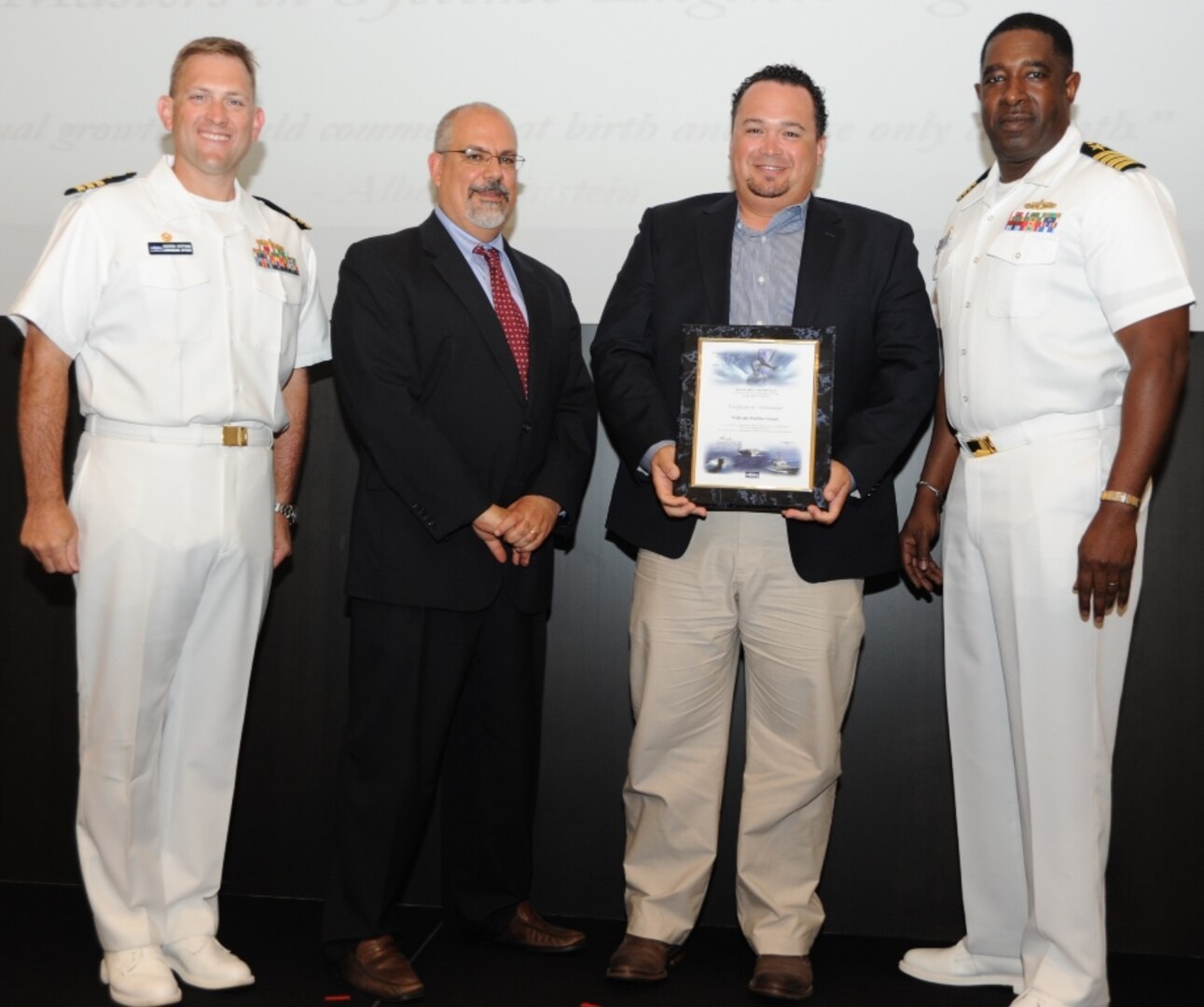 IMAGE: DAHLGREN, Va. - Wilfredo Padilla-Vargas receives his certificate of achievement from Naval Surface Warfare Center Dahlgren Division (NSWCDD) Technical Director John Fiore, NSWCDD Commanding Officer Capt. Godfrey 'Gus' Weekes, right, and Combat Direction Systems Activity Dam Neck Commanding Officer Cmdr. Andrew Hoffman at the 2017 NSWCDD academic awards ceremony. Padilla-Vargas was recognized for completing his master's in systems engineering from the Naval Postgraduate School, and commended for his commitment to personal and professional development.
