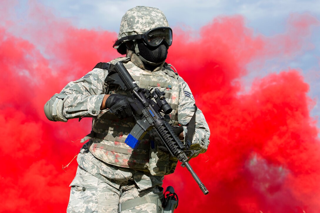 A reserve airman rushes to their next firing objective under the cover of red smoke while participating in training to shoot, move and communicate.