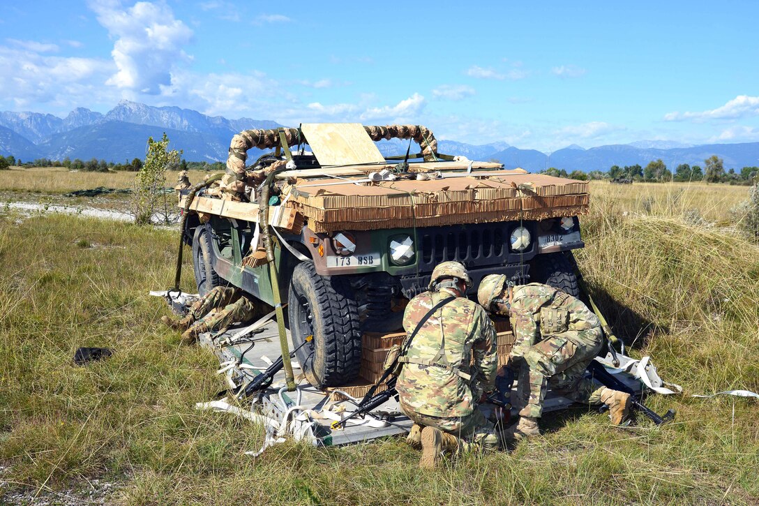 Soldiers remove packing while recovering a Humvee after being dropped from an Air Force C-130 Hercules aircraft.