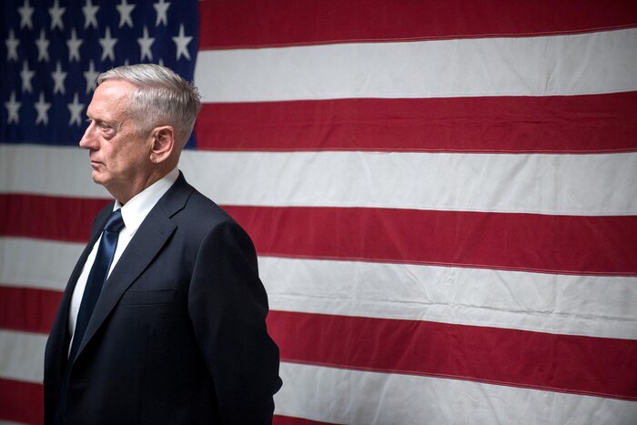 Defense Secretary Jim Mattis stands in front of an American flag.
