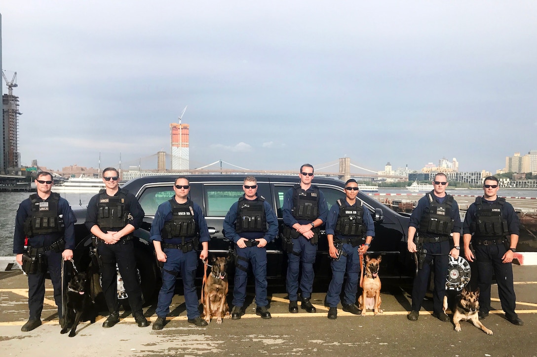 Coast Guard members pose for a photograph before conducting explosives detection operations with their detection dogs, Cappy, Ryder, Ruthie, and Digo.